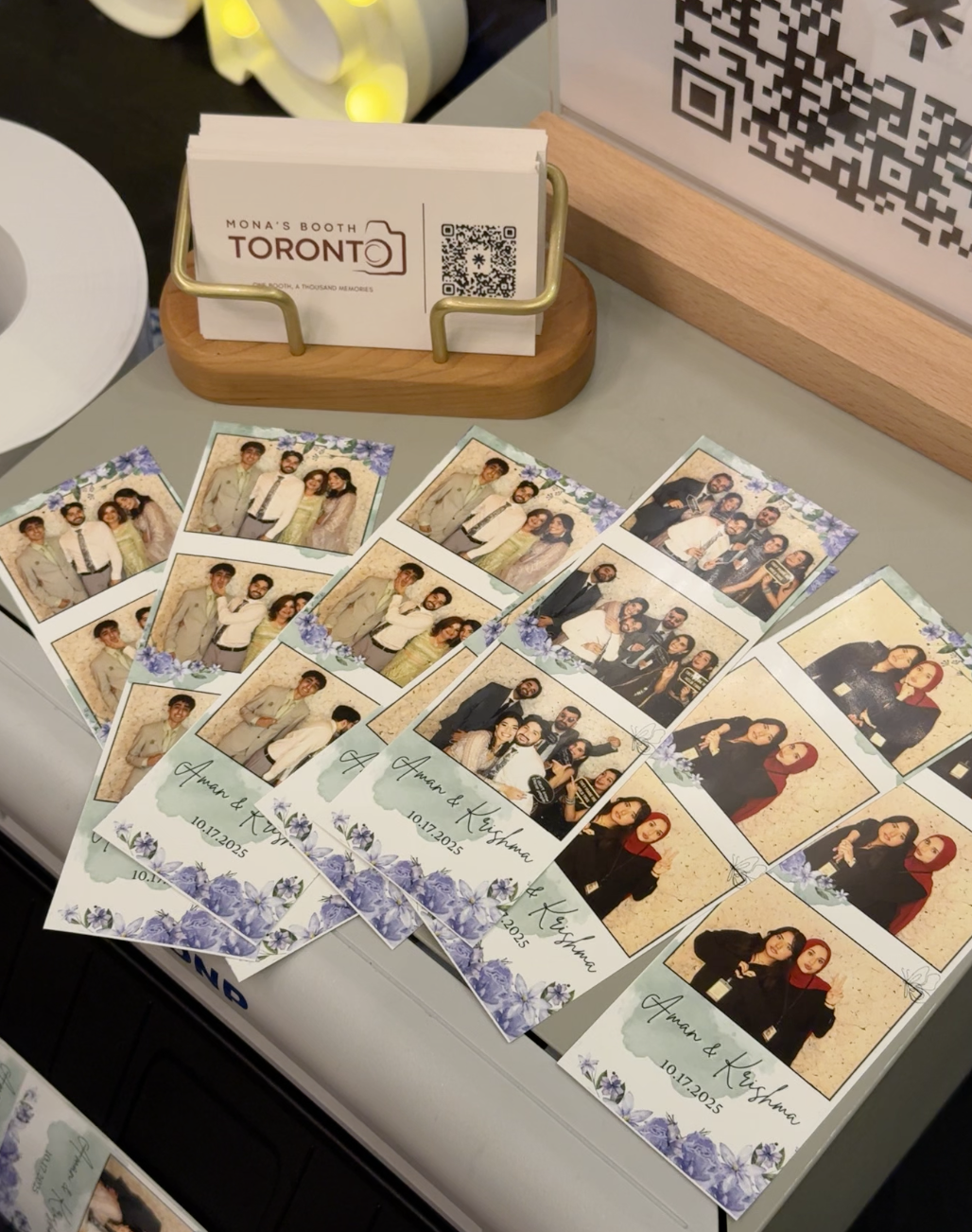 Custom Aman & Krishma photo strips laid out beside Mona's Booth Toronto business cards