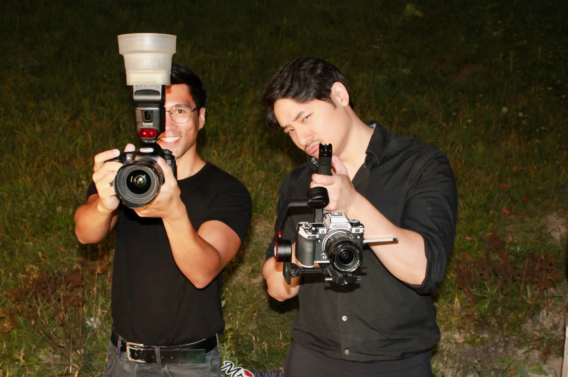 Two photographers posing with a DSLR camera and a video camera on a gimbal